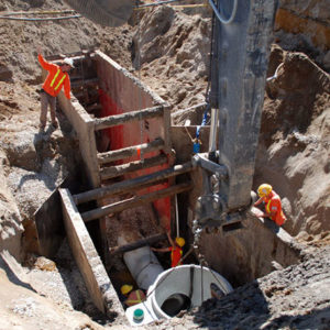 Excavator placing sewer sections into hole