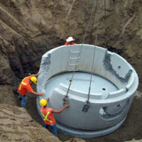 Crew placing concrete ring onto foundation
